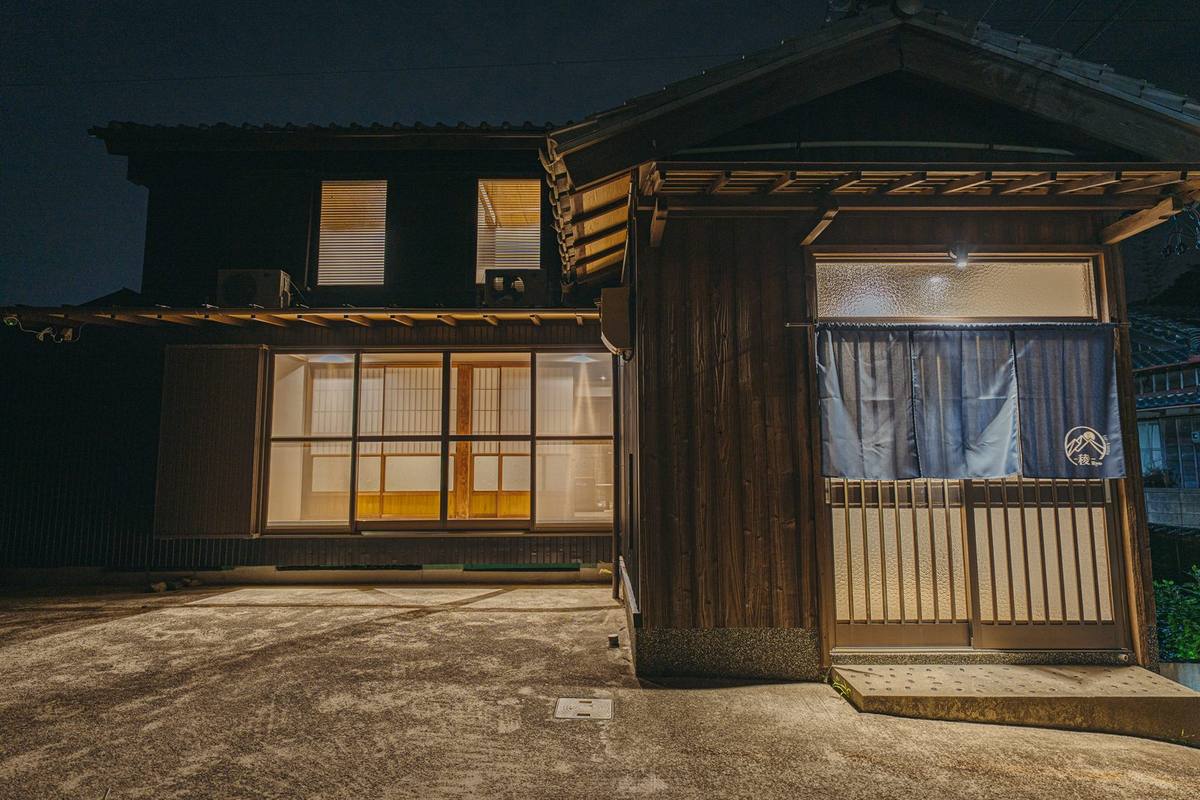 夜の朝熊 -稜- Ryo 正面。明かりの灯った木造の建物と、暖簾のかかった玄関